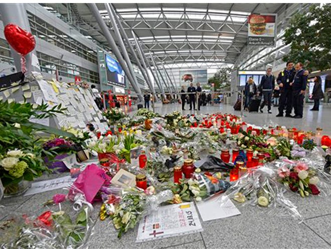 Passengers watch candles and flowers for the victims of the plane crash at the airport in Dusseldorf , Germany on Tuesday. One week ago 150 people died in the Germanwings airliner crash in the French alps from Barcelona to Duesseldorf. (