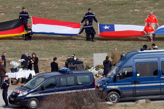 Flags representing differents nations are deployed during an homage ceremony with family members of victims, in front of a stele, a stone slab erected as a monument, set up in memory of the victims in the area where the Germanwings jetliner crashed in the French Alps, in Le Vernet, France, Sunday, March 29, 2015. The crash of Germanwings Flight 9525 into an Alpine mountain Tuesday killed all 150 people aboard, and has raised questions about the mental state of the co-pilot. Authorities believe the 27-year-old German deliberately sought to destroy the Airbus A320 as it flew from Barcelona to Duesseldorf. (AP Photo/Claude Paris)