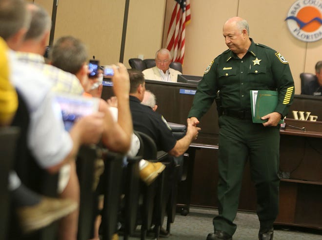 Bay County Sheriff Frank McKeithen shakes hands with Panama City Beach Police Chief Drew Whitman after addressing the Bay County Commission in Panama City on Tuesday.