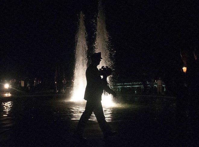 A man in uniform walks by the Twin Fountains during the Garden of Reflection Remembrance in Light Ceremony on Thursday night in Lower Makefield.