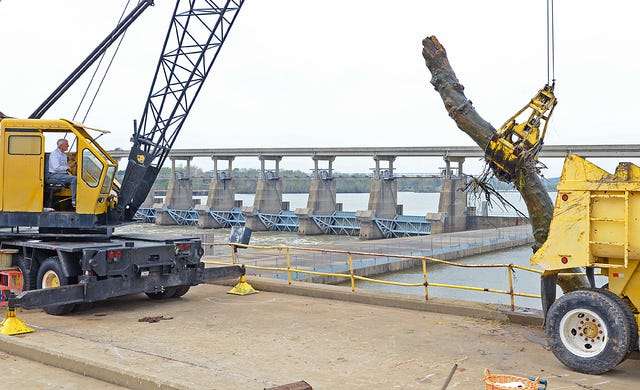 BRIAN D. SANDERFORD • TIMES RECORD Jay Gipson with Gipson Crane Service removes debris from the Arkansas River at the Clyde T. Ellis Hydroelectric Generating Station at the James W. Trimble Lock and Dam on Wednesday, April 1, 2015. Gipson of Van Buren said he has been operating the crane service since 1959.