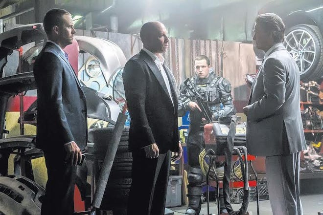 (L to R, foreground) Brian (PAUL WALKER) and Dom (VIN DIESEL) meet with a high-level government operative (KURT RUSSELL) in ?Furious 7?. Continuing the global exploits in the unstoppable franchise built on speed, James Wan directs this chapter of the hugely successful series.