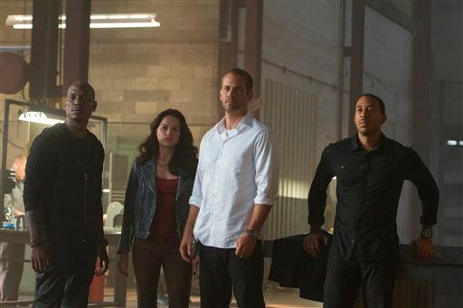 This photo provided by Universal Pictures shows, from left, Tyrese Gibson as Roman, Michelle Rodriguez as Letty, Paul Walker as Brian, and Chris Ludacris as Tej, in a scene from "Furious 7." (AP Photo/Universal Pictures, Scott Garfield)