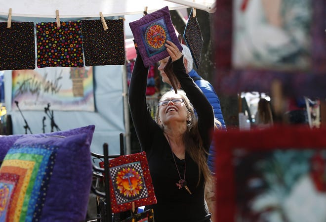 Kris Daly hangs the hot pads she sells from her booth at Eugene’s Saturday Market. (Andy Nelson/The Register-Guard)
