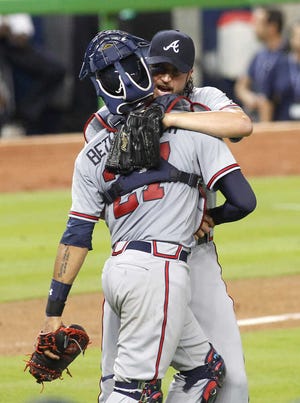 Atlanta Braves relief pitcher Jason Grilli celebrates his save with catcher Christian Bethancourt (27) after the Braves defeated the Marlins 2-1 in their opening day baseball game in Miami, Monday, April 6, 2015. (AP Photo/Joe Skipper)
