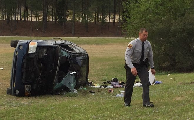 Trooper B.D. Freeman investigates the crash of an SUV that ran off the exit ramp from N.C. 24 onto Interstate 95, causing it to roll over several times. Monday, April, 6, 2015.