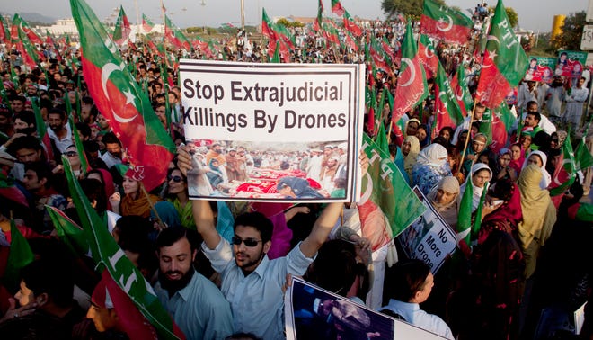 FILE - In this Oct 28, 2011 photo, supporters of Pakistani politician Imran Khan rally to condemn U.S. drone attacks in Pakistani tribal areas on al-Qaida and Taliban hideouts, in Islamabad, Pakistan. A Pakistani judge on Tuesday ordered criminal charges be filed against a former top CIA lawyer who oversaw its drone program and a former station chief in Islamabad over a 2009 strike that killed two people.