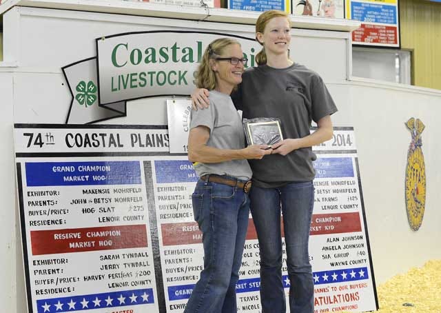 Makensie Mohrfed, right, accepts the leadership award from Miriam Lewis, Pitt County 4-H volunteer, at the Coastal Plains Junior Livestock Show on Tuesday at the Lenoir County Livestock Arena.