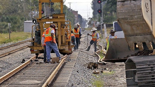 Men work on the Florida East Coast railroad tracks along Federal Highway, just south of Gateway Boulevard, on Jan. 13, 2015. (Bill Ingram / Palm Beach Post)