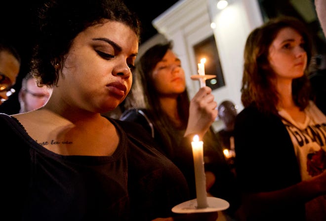 Jasmine Huber, left, of North Charleston, S.C., observes a moment of silence during a candlelight vigil outside city hall protesting the shooting death of Walter Scott, Wednesday, April 8, 2015, in North Charleston, S.C.