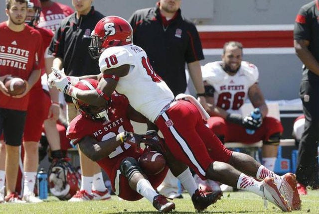 SPRING ACTION — N.C. State running back Matt Dayes (21), with the red team, pulls in a reception as safety Freddie Phillips, Jr. (10) tackles him during the 2015 Kay Yow Spring Game at Carter-Finley Stadium.
