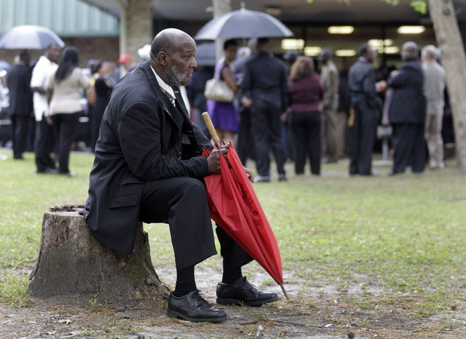 Eddie Bryan sits on a stump outside the World Outreach Revival Deliverance Ministries Christian Center before the funeral service in Summerville, S.C., Saturday, April 11, 2015 for Walter Scott, who was killed by a North Charleston, S.C., police officer last Saturday after a traffic stop. Bryan was a co-worker of Scott’s but was not sure if he could get inside for the service.