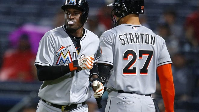 Miami Marlins Adeiny Hechavarria, left, celebrates with Giancarlo Stanton (27) after scoring off of a ground out of Christian Yelich in the third inning of a baseball game against the Atlanta Braves, Monday, April 13, 2015, in Atlanta. (AP Photo/Todd Kirkland)