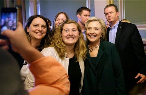 Democratic presidential candidate Hillary Rodham Clinton poses for a photo with Simpson College student MacKenzie Bills, center, after meeting with Iowa Democratic Party lawmakers at the Statehouse, Wednesday, April 15, 2015, in Des Moines, Iowa. (AP Photo/Charlie Neibergall)