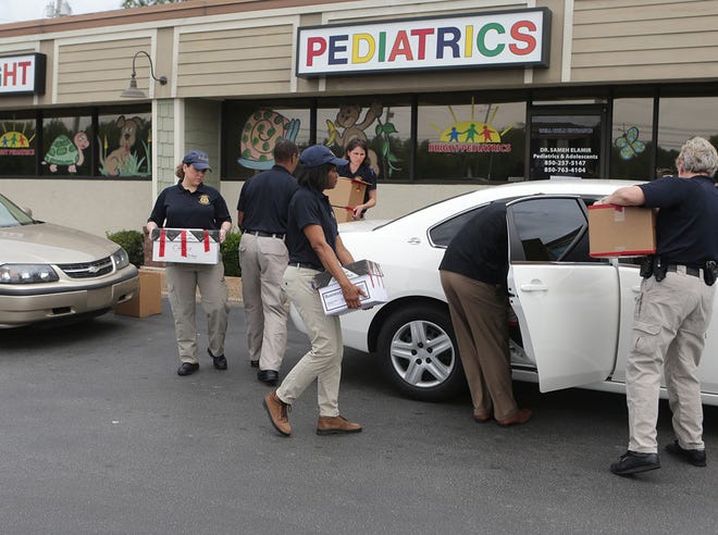 The Medicaid Fraud Control Unit of the Attorney General's Office carries paperwork out of Bright Pediatrics on Wednesday at the 23rd Street office.