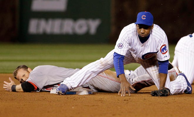 Chicago Cubs second baseman Jonathan Herrera, right, looks to first base after forcing out Cincinnati Reds' Zack Cozart at second base during the eighth inning of a baseball game in Chicago, Wednesday, April 15, 2015. Cincinnati Reds' Kristopher Negron was safe at first. (AP Photo/Nam Y. Huh)