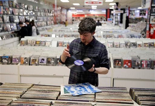 Record clerk Josh Kelly wipes a dust speck from a used LP record as he put it in a sales bin at Vintage Vinyl Records Tuesday, April 14, 2015, in Fords, N.J. A recent Rutgers graduate, Kelly is working at the record store and living with friends while he tries to land a job in journalism or radio programming. (AP Photo/Mel Evans)