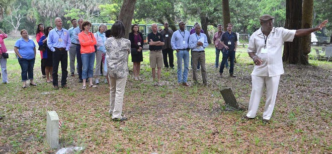 PETER.WILLOTT@STAUGUSTINE.COM Greg White, right, talks to participants in the Jacksonville Area Legal Aid's Fair Housing Civil Rights Bus Tour about the historical significance of the Pinehurst Cemetery in West Augustine during a tour of the community on Friday, April 17, 2015. This year's theme for the tour was A Tale of Three Cities: Ancient, Civil Rights and Modern. The tour focused on key historical sites in the St. Augustine African-American communities of West Augustine and Linconville.