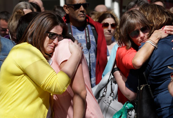 Jenna Dziedzic, of Boston, left, hugs Sabrina Dellorusso, also of Boston, second from left, as Linda Witt, of Neenah, Wis., second from right, hugs Jillian Boynton, of Manchester, N.H., right, during a moment of silence at one of two blast sites near the finish line of the Boston Marathon, in Boston, Wednesday, April 15, 2015. All four women were near the finish line of the Boston Marathon in 2013 where a friend, Roseann Sdoia, lost a limb during the explosion. (AP Photo/Steven Senne)