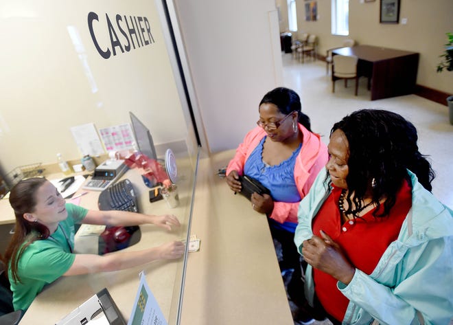 Tieannaca Lewis, middle, pays discounted court costs for her mother Jennifer Tooson, right, on Saturday to clerk Sumer Laurenza at the Okaloosa County Courthouse Annex Extension. The extra money owed for overdue tickets, court fees and fines in Florida were waived during the one-day event called Operation Green Light.