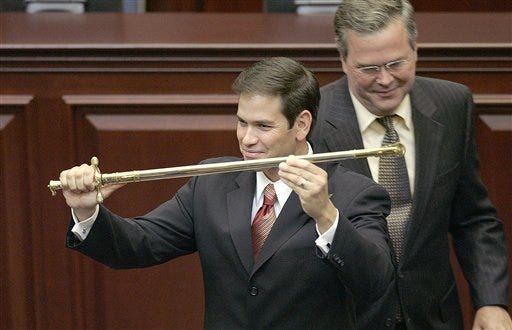 In this Sept. 13, 2005, file photo, then-Rep. Marco Rubio, R-Miami, left, holds a sword presented to him by then-Gov. Jeb Bush, right, during ceremonies designating Rubio as the next Florida Speaker of the House in Tallahassee. Devoted political allies for more than a decade, the alliance between Bush and Rubio is beginning to splinter as the one-time mentor and his political protégé face off in the race for the Republican presidential nomination.