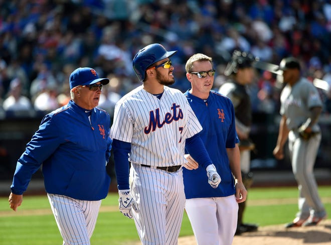 Mets manager Terry Collins, left, and a Mets trainer talk with catcher Travis d'Arnaud (7) after he was hit by a pitch thrown by Marlins reliever A.J. Ramos, on Sunday in New York. d'Arnaud left the game with a fractured right hand. Associated Press