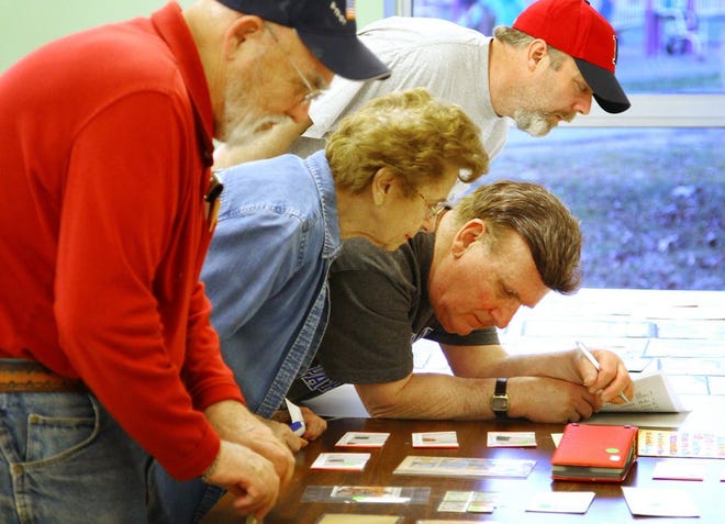 Stamps up for auction get close looks at a Granite City Stamp Club meeting. From left are club members Bruce Bent, Carmela Varraso, Frank Jesonis and Ed Bohn. The photo was taken on Wednesday, April 15, 2015.