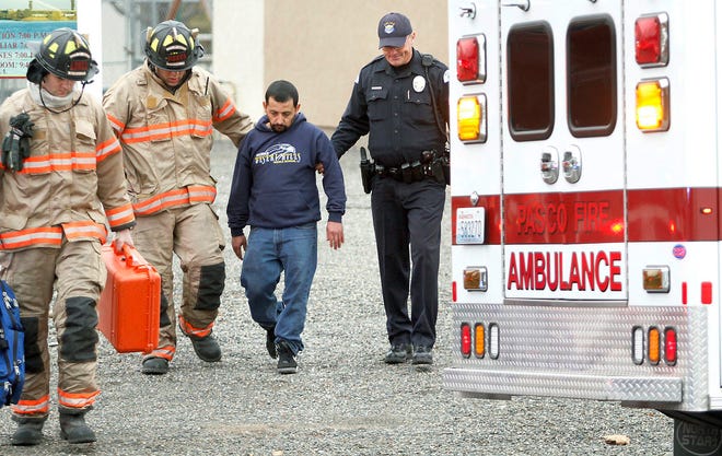 In this Jan. 22 photo, Pasco firefighters and Dean Perry, right, a Pasco police officer, help Antonio Zambrano-Montes, second from right, to an ambulance following a house fire.
