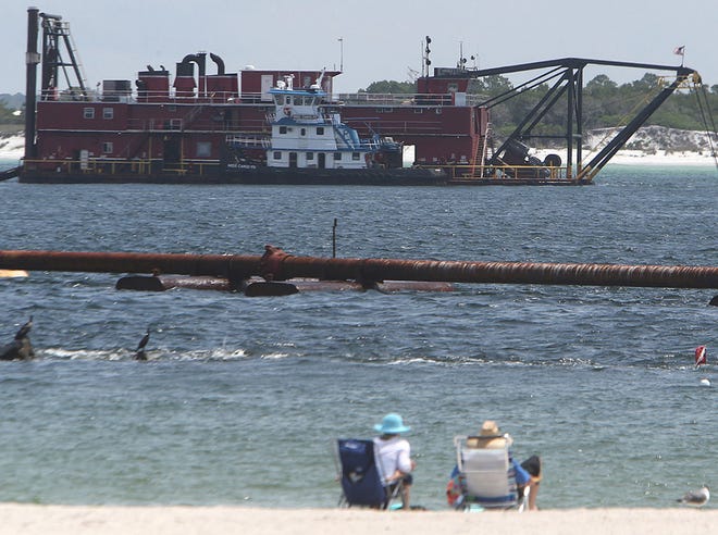 Beach visitors watch from “the kiddie pool” area as a dredge pumps sand from St. Andrew Pass onto the beaches of the state park Friday.