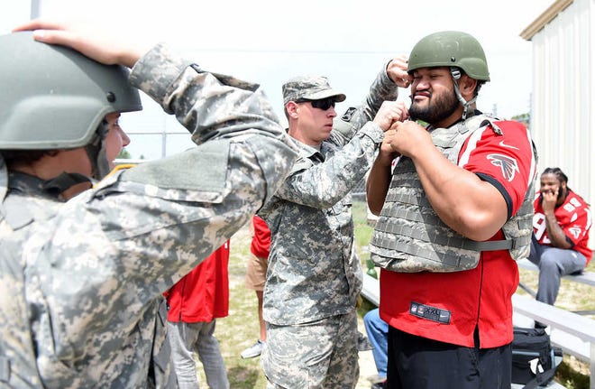 Sgt. Vinson Downer gets Atlanta Falcons defensive tackle Ricky Havili-Heimuli ready to go into a humvee simulator Thursday during a military appreciation event at Fort Gordon. Head coach Dan Quinn also visitied.