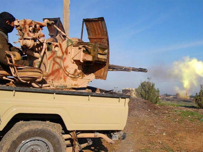 In this image posted on a militant social media account by the Al-Baraka division of the Islamic State group on Feb. 24, a fighter fires a heavy weapon mounted on the back of a pickup truck during fighting in Tal Tamr, Hassakeh province, Syria. Fierce fighting took place between Kurdish and Christian militiamen and Islamic State militants