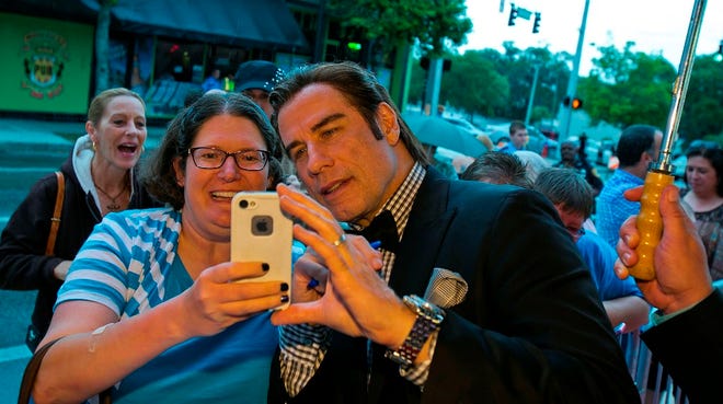 Kelly Dunn, left, takes a selfie with John Travolta as she and about 50 people waited along the red carpet in front of the Marion Theatre in hopes of getting selfies and autographs from John Travolta for the premiere of his new movie "The Forger" on April 19.