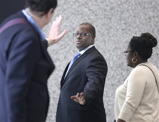 Illinois state Rep. Derrick Smith, center, waves as he enters federal court for the beginning of jury selection in his corruption trial Wednesday, May 28, 2014, in Chicago. (AP Photo/M. Spencer Green)