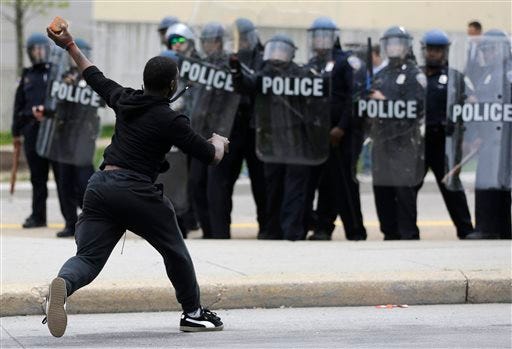 A man throws a brick at police Monday, April 27, 2015, following the funeral of Freddie Gray in Baltimore. (AP Photo/Patrick Semansky)