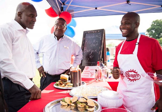Chef Richie Crooks (right) talks to retired boxer Evander Holyfield about his "Evander's knock-out burger," which he cooked up at the Boys and Girls Clubs of the CSRA's annual Burger Battle, where Holyfield was the guest host.