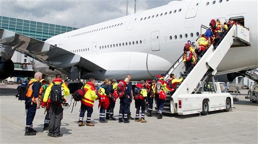 Members of a German rescue organization board a plane at the airport in Frankfurt, central Germany, Sunday, April 26, 2015, for their flight to earthquake-torn Nepal. International Search and Rescue Germany says a team of 52 relief workers including doctors, experts trained in searching for people buried under rubble and several dog squads will fly to Nepal.