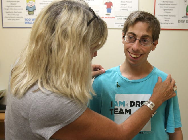 Karen Tannen adjust a pin on her son Joshua Tannen’s shirt. Joshua Tannen had his first kidney transplant at the age of 14.
