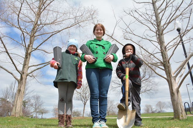 Charlotte and Lillian Cain hold seedlings while Dylan Rauktis is ready to shovel.
