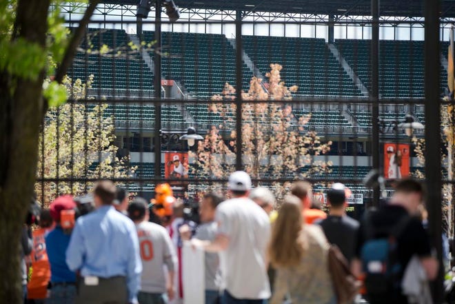 Fans watch through a fence outside Oriole Park at Camden Yards as the Baltimore Orioles play a baseball againse Chicago White Sox Wednesday, April 29, 2015, in Baltimore. The game was played in an empty ballpark amid unrest in the city over the death of Freddie Gray while in police custody.