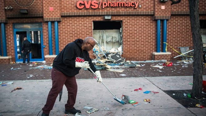 Jerald Miller helps clean up debris from a CVS pharmacy that was set on fire during rioting after the funeral of Freddie Gray, on Tuesday in Baltimore. Gray, 25, was arrested for possessing a switch blade knife April 12 outside the Gilmor Houses housing project on Baltimore’s west side. According to his attorney, Gray died a week later in the hospital from a severe spinal cord injury he received while in police custody. (Andrew Burton/Getty Images)