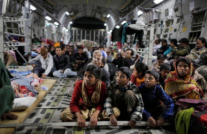 Survivors of Saturday's earthquake hold on to a cable as a military takes off with evacuees from Kathmandu to New Delhi during a midnight rescue mission by Indian Air Force, in Kathmandu, Nepal, Wednesday, April 29, 2015.