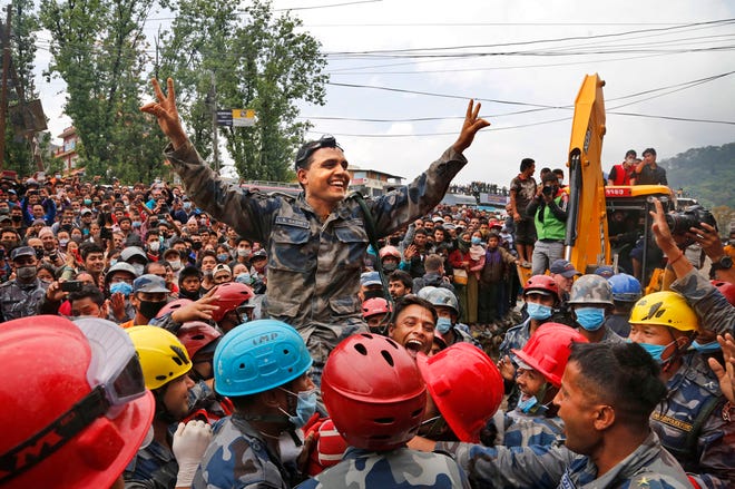 Nepalese policemen lift their commander and celebrate after they along with U.S. rescuers pulled out Pemba Tamang, a teenage boy from a building that collapsed five days ago in Kathmandu, Nepal, Thursday, April 30, 2015. Crowds cheered Thursday as Tamang was pulled, dazed and dusty, from the wreckage of a seven-story Kathmandu building that collapsed around him five days ago when an enormous earthquake shook Nepal.