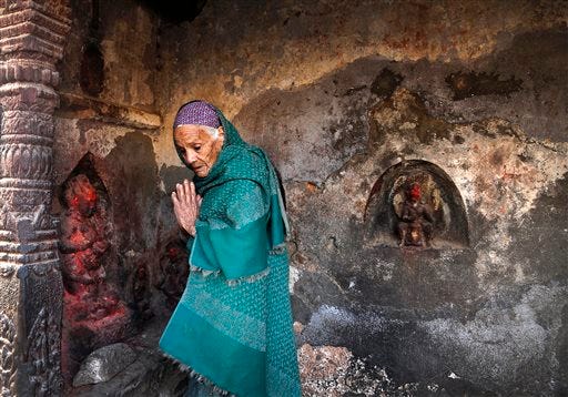 An elderly Nepalese woman prays at a temple damaged in an earthquake in Kathmandu, Nepal, Friday, May 1, 2015. The strong magnitude earthquake shook Nepal on Saturday devastating the region and leaving some thousands shell-shocked and displaced. (AP Photo/Manish Swarup)