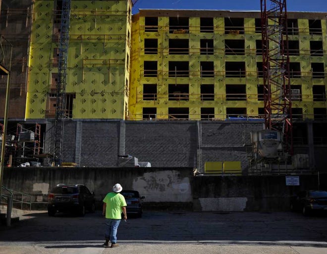 A construction worker looks to the top floors of the construction site for the Georgia Heights apartment complex while smoking a cigarette on Wednesday, Feb. 11, 2015, in Athens, Ga. (AJ Reynolds/Staff, @ajreynoldsphoto)