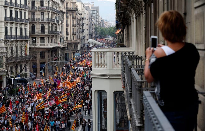 A woman takes a picture with her phone as people protest during a May Day rally in the center of Barcelona, Spain, Friday, May 1, 2015. May 1 is celebrated as International Labor Day or May Day across the world.