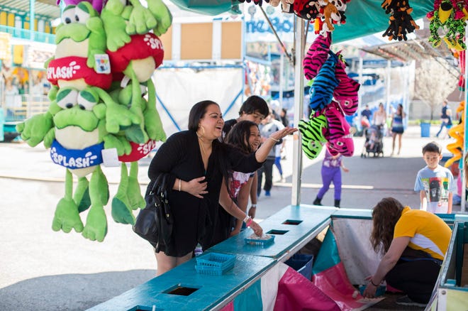 Lind Bholla of Zeeland and Asianna Delacruz of Zeeland play the Gold Fish Game on Saturday, May 2, 2015 at the carnival in downtown Holland. Emily Brouwer/Sentinel Staff
