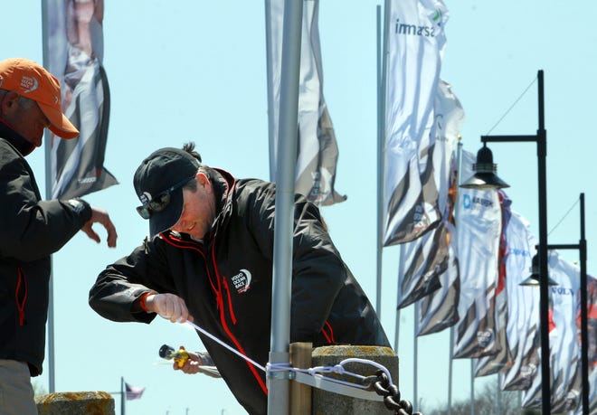 Amo Ross, left, a Sail Newport board member, and Brad Read, right, executive director of Sail Newport, tighten flagpoles around the temporary village being constructed at Fort Adams for the race's stopover in Newport. 

The Providence Journal/Bob Breidenbach