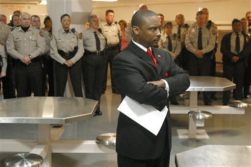 FILE -In this Thursday, Jan. 13, 2005 file photo, Newly sworn-in Clayton County Sheriff Victor Hill, foreground, stands with arms folded after speaking to his deputies in Jonesboro, Ga. Hill, who was acquitted three years ago in a major public corruption case is now accused of shooting a woman, Sunday, May 3, 2015, in a subdivision near the suburb of Lawrenceville, Ga. he shooting was "reported as accidental," police said late Sunday in a statement, which did not elaborate on who characterized it that way. (Zach Porter/Clayton Daily News, File via AP)