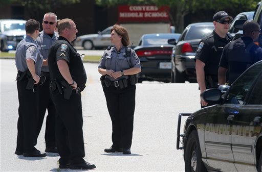 Conyers Police and Rockdale County Sheriff's deputies block the exit from Conyers Middle School on Tuesday, May 5, 2015 after a shot was fired inside the school in Conyers, Ga. Cpl. Michael Camp with the Rockdale County Sheriff's office says a single shot was fired inside a boys' restroom at the school. Camp says a student has been taken into custody, and no injuries have been reported. (Ben Gray/Atlanta Journal-Constitution via AP)