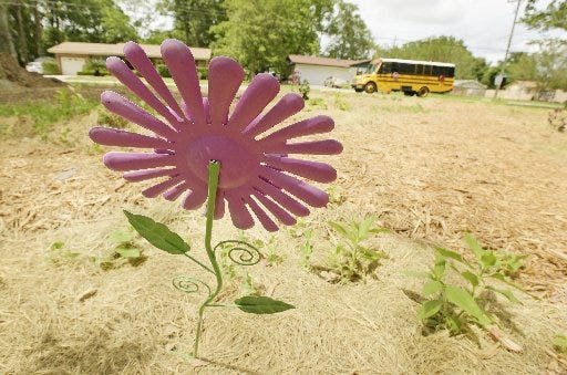 A metal flower, painted purple because it was Somer Thompson's favorite color, stands in the garden planted on the Gano Avenue lot in Orange Park where the house that 7-year-old Somer was murdered in used to stand. Saturday will be a ribbon-cutting for the community garden there to honor Somer.